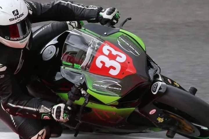 A bikes on a black/green motorbike riding around a corner