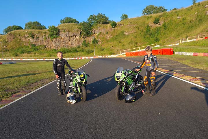 2 youth motorbike riders standing next to their motorbikes