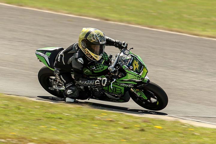 A biker on a black motorbike riding around a corner